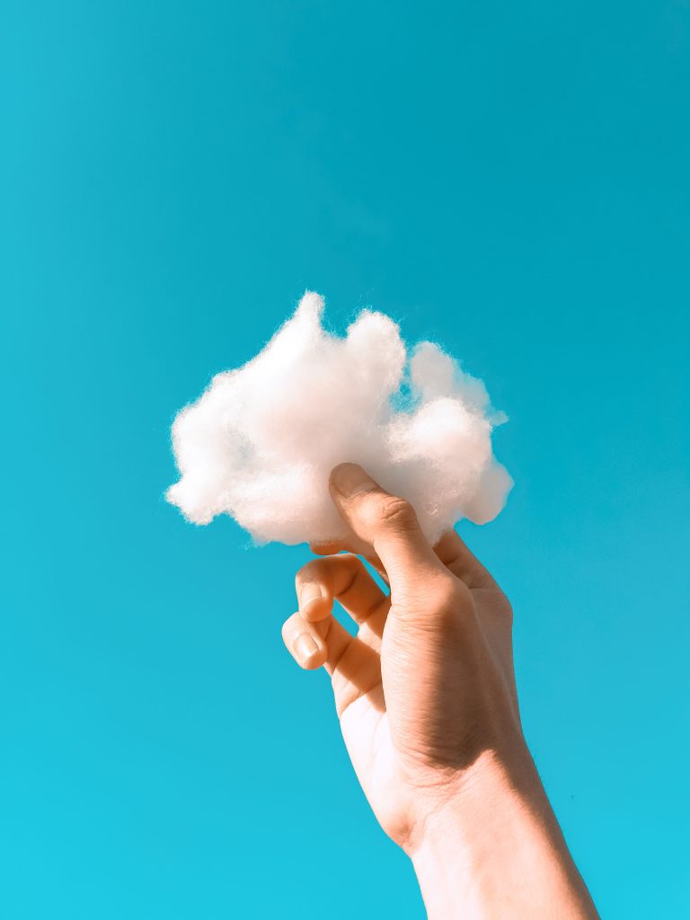 pexels photo 5371764 5371764 A hand holding a fluffy cotton-like cloud against a bright blue clear sky.